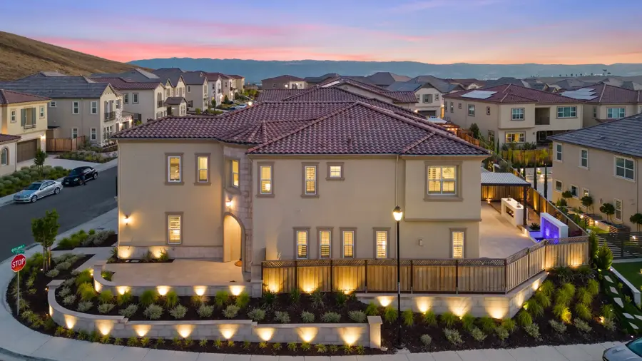 Twilight drone view of a large tile-roof home and landscaped yard