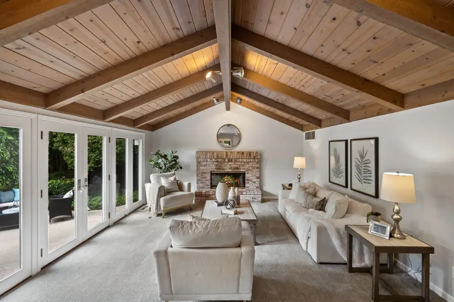 Bright living room with vaulted wood-beam ceiling and fireplace, real estate photography