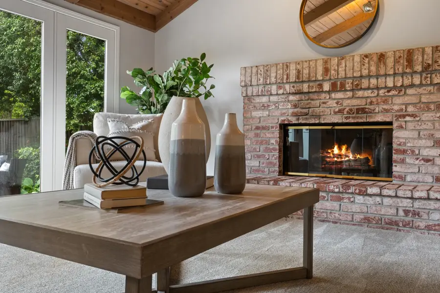 Staged coffee table in front of a brick fireplace, interior detail shot