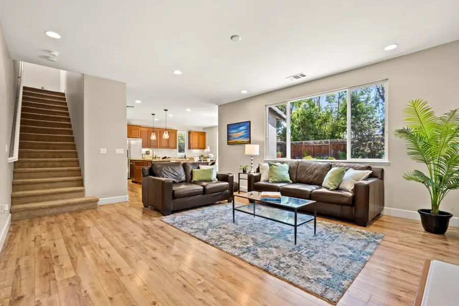 Open living room with leather sofas, hardwood floors and staircase