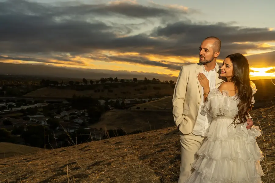 Couple posing on a hilltop at sunset overlooking the valley