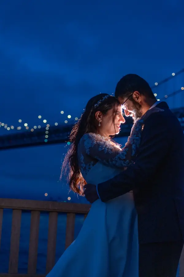 Couple forehead to forehead at blue hour with bridge lights behind
